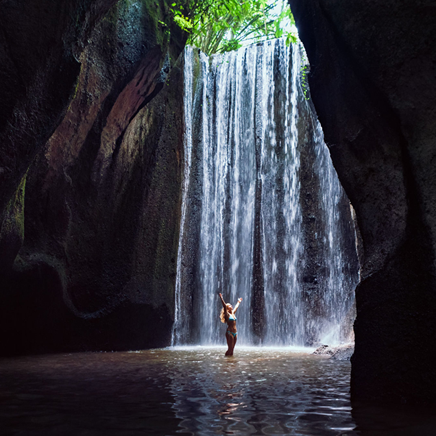 woman-stand-under-cave-waterfall-bali-636×636